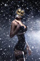 A woman in erotic clothes and a mask on a snowy background