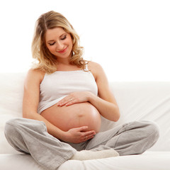 A young blond pregnant woman sitting in indoor clothes