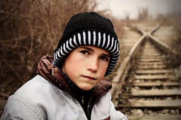 Warm gekleideter Junge auf verlassenen Gleisen