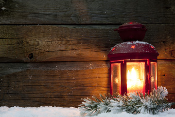 Christmas lantern light in night on snow and wooden boards