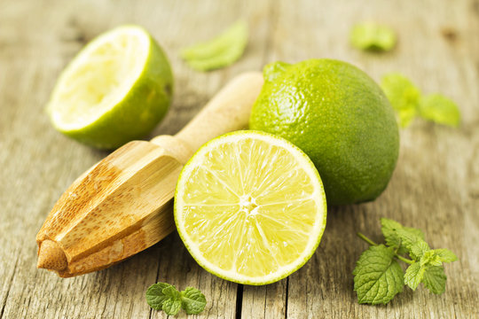 Fresh Limes With A Reamer On Wooden Table