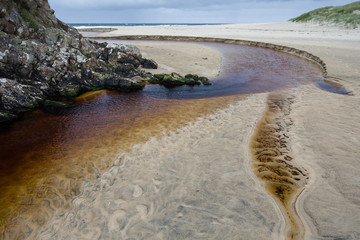 Iron coloured stream flowing into the sea.