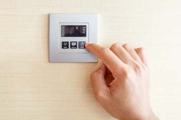 Hand with finger on air conditioner switch control