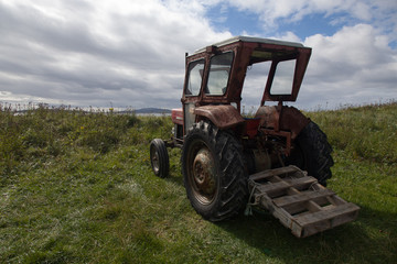 Rusty old red tractor by the sea