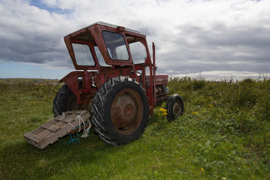 Rusty old red tractor by the sea