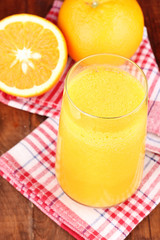 Glass of fresh orange juice on wooden table
