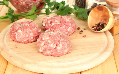 Raw meatballs with spices on wooden table
