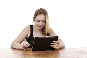 Pretty young girl sitting by table working on tablet computer