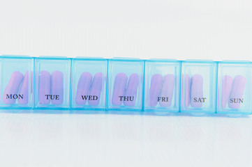 Pink capsule in blue daily pill box