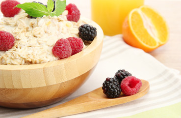 tasty oatmeal with berries and glass of juice, on wooden table