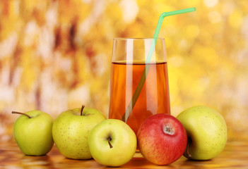 Useful apple juice with apples around on autumn background