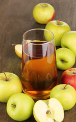 Useful apple juice with apples around on wooden table