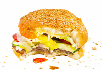 Bitten burger with vegetables and crumbs isolated on white