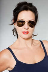 Pretty brunette woman with sunglasses studio shot.