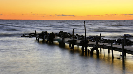 Obraz premium Sunset at sea behind boat bridge