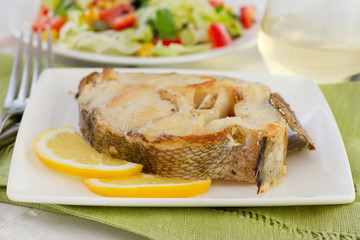 fish with lemon and salad on the plate