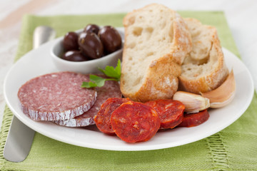 sausages with bread and olives on the white plate
