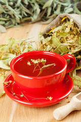 cup of linden tea and flowers in canvas bag on wooden table