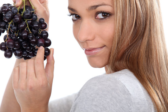 a young woman savouring sensually a grape