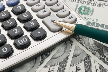 calculator and pen on us paper currency