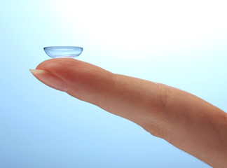 contact lens on finger on blue background