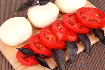 tasty mozzarella with tomatoes on chopping board on mat