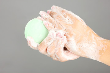 Woman's hands in soapsuds, on gray background close-up