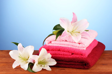 Obraz na płótnie Canvas stack of towels with pink lily on blue background.