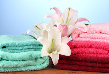 Obraz na płótnie Canvas stack of towels with pink lily on blue background.