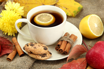 cup of hot tea and autumn leaves, on burlap background