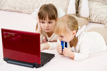 Two little girls are with a laptop and a credit card