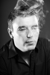 Fototapeta premium Smoking man with short brown hair. Black and white studio shot.