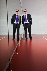 Fototapeta premium Cool looking business man with sunglasses against mirror in gym.