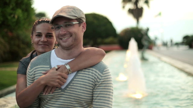 Happy couple in love sitting by the fountain, steadicam shot