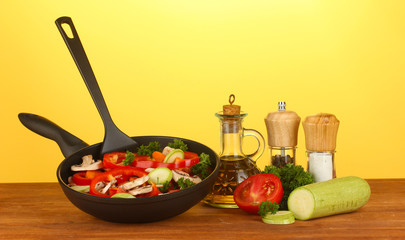 frying pan with vegetables on yellow background