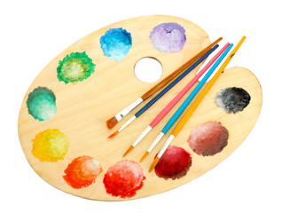 wooden art palette with paint and brushes isolated on white