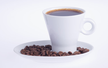 coffee in a cup on a saucer covered with coffee beans