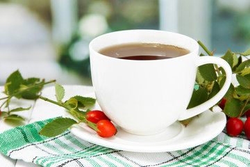 cup of tea with hip roses, on wooden table