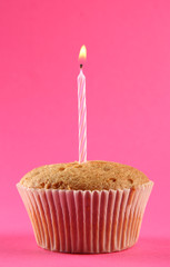tasty birthday cupcake with candle, on pink background