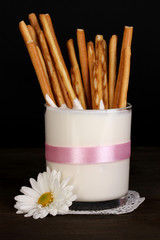 Tasty crispy sticks in glass with sour cream isolated on black
