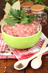 Bowl of raw ground meat with spices on wooden table