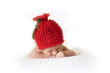 cute newborn baby in a red berry cap on white background