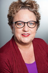 Smiling senior woman with short curly hair. Wearing glasses.