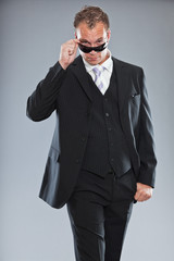 Macho business man with short hair wearing black sunglasses.