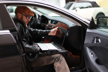 Mann sitzt im Auto mit Laptop - obrazy, fototapety, plakaty