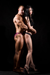 Muscular man and a woman posing in studio