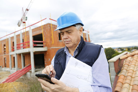 Construction manager on building site using smartphone