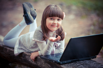 Child in autumn park with laptop
