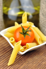 Raw penne pasta in a small bowl, selective focus