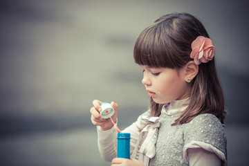 Portrait of funny lovely little girl blowing soap bubble